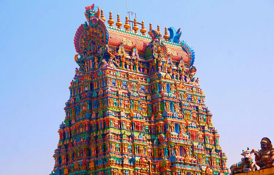 Wieża (gopura) świątyni Meenakshi z bogatymi i kolorowymi rzeźbami hinduskimi w Maduraju (Indie), na tle niebieskiego nieba
