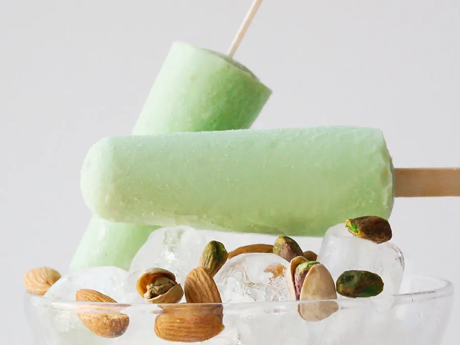 Zielone kulfi miętowo-pistacjowe podane na lodzie z pistacjami i migdałami.