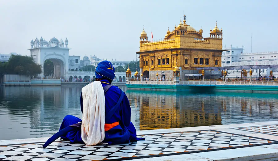 Mężczyzna (Sikh) w tradycyjnym stroju medytuje przed Złotą Świątynią w Amritsar (Indie) - główną świątynią sikhizmu