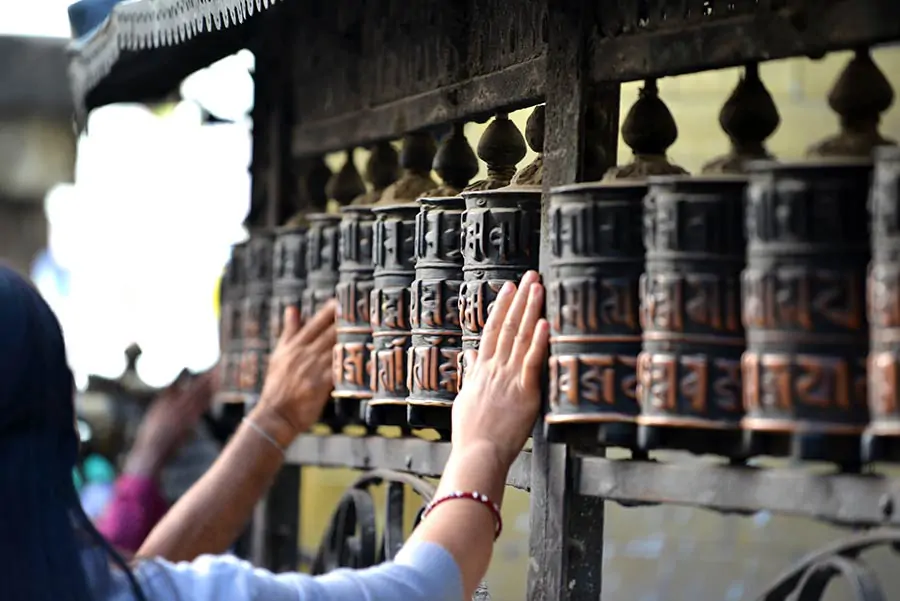 Metalowe buddyjskie koła modlitewne w Nepalu, z wyrytą mantrą Om Mani Padme Hum, obracane przez ręce wiernych.