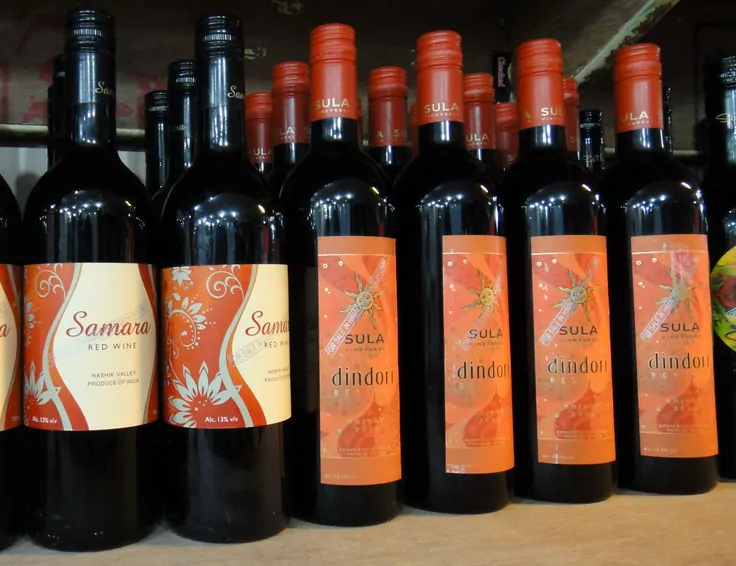 Butelki indyjskiego wina Suna ustawione w rzędzie na półce sklepowej.