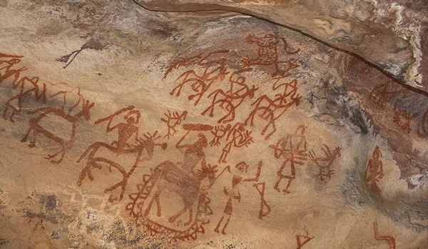Malowidła naskalne w jaskiniach Bhimbetka w górach Windhja, Indie, przedstawiające prymitywne sceny z życia ludzi prehistorycznych, w tym postaci ludzkie i zwierzęta.